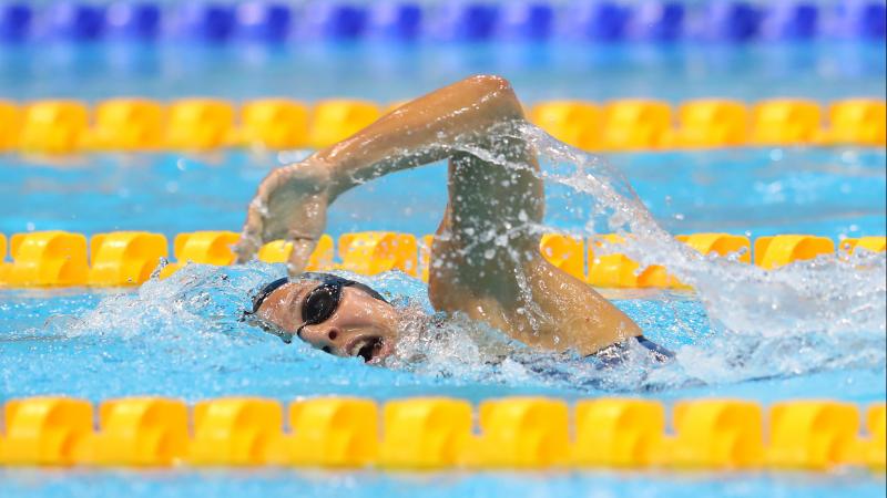 a female Para swimmer doing freestyle and taking a breath