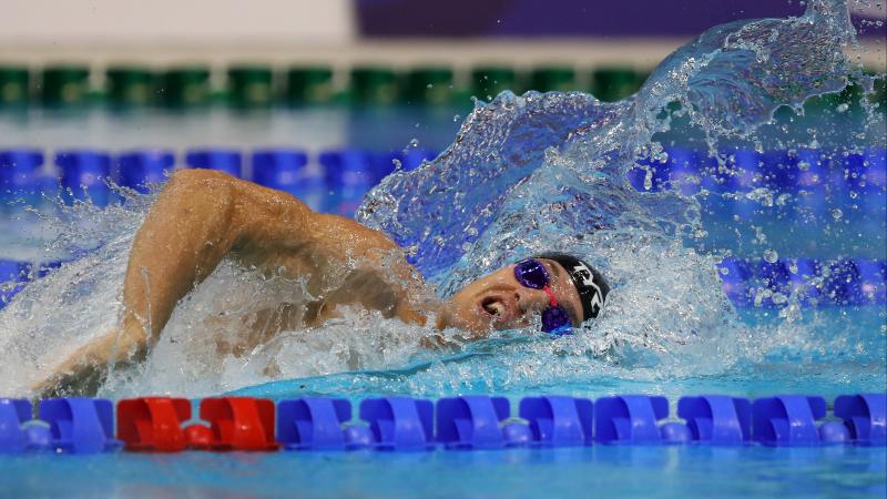 a male Para swimmer competing in a freestyle race