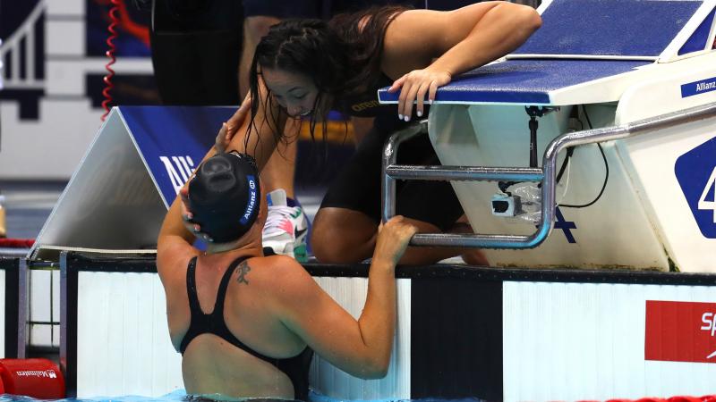 Woman in water celerbates with teammate who is on deck