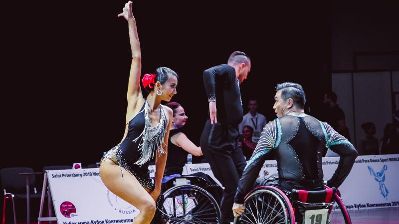 Female standing dancer dances with male wheelchair partner 