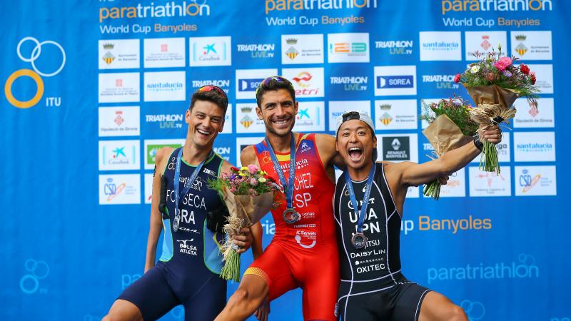 Three male Para triathletes have fun posing for a podium photo