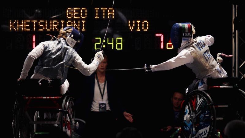 Two women in wheelchairs fencing