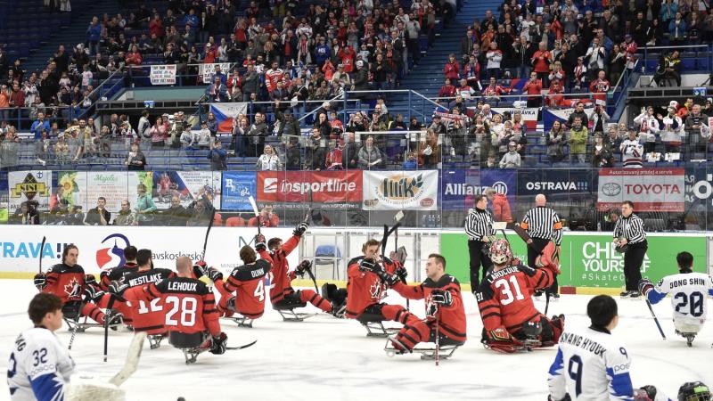 Canada hockey team celebrates on ice while South Korean team looks on