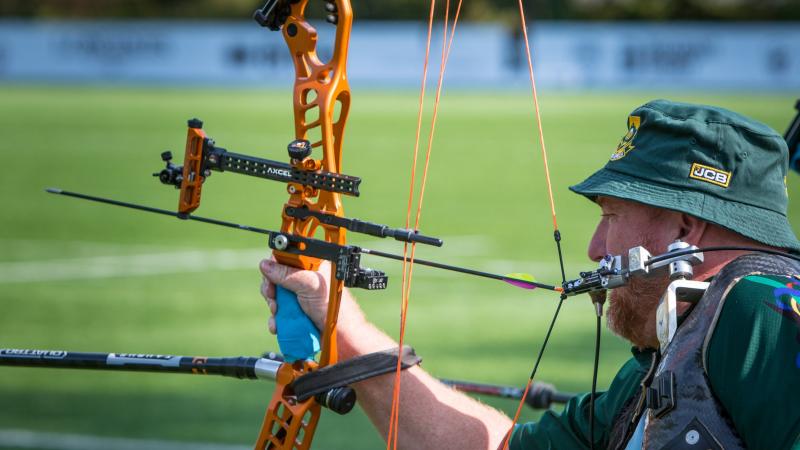 Male archer with missing left arm shoots arrow with mouth