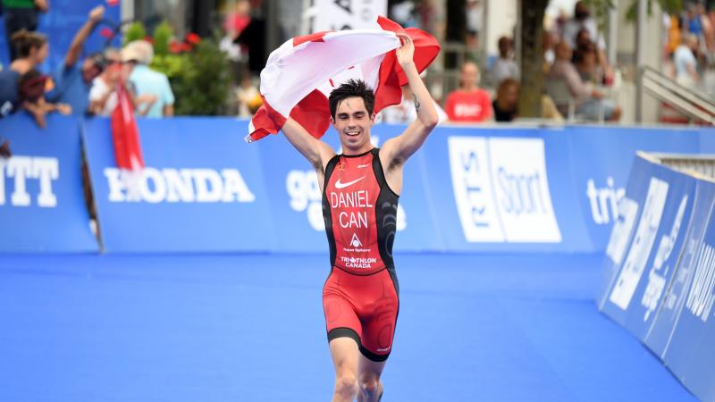 Male triathlete with arm disability holds Canadian flag