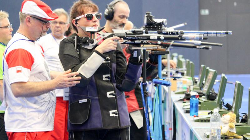 Female vision impaired rifle shooting athlete receives guidance from loader