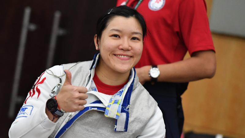 Hong Kong female fencer smiles and gives thumbs up