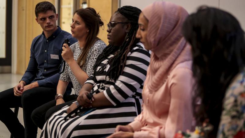 Speakers sitting next to each other with one of them talking with a microphone