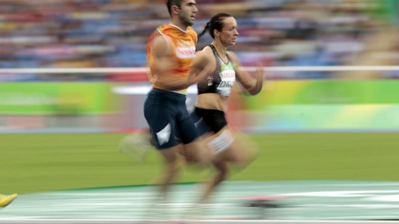 A female sprinter next to her guide on an athletics track