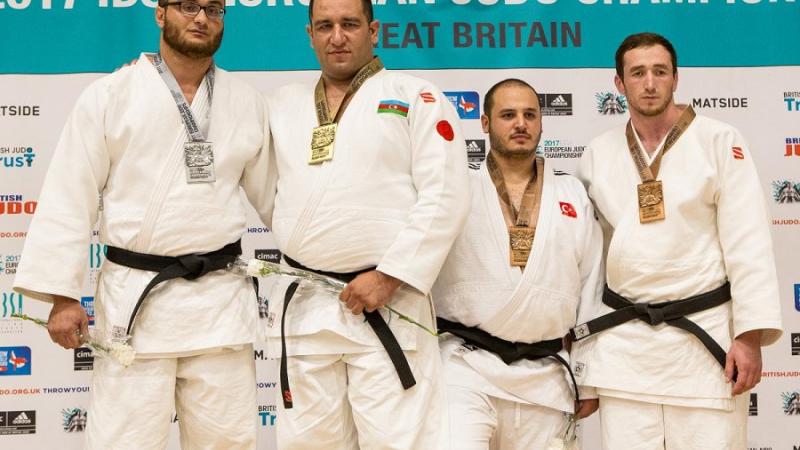 Four male medal winners on a podium