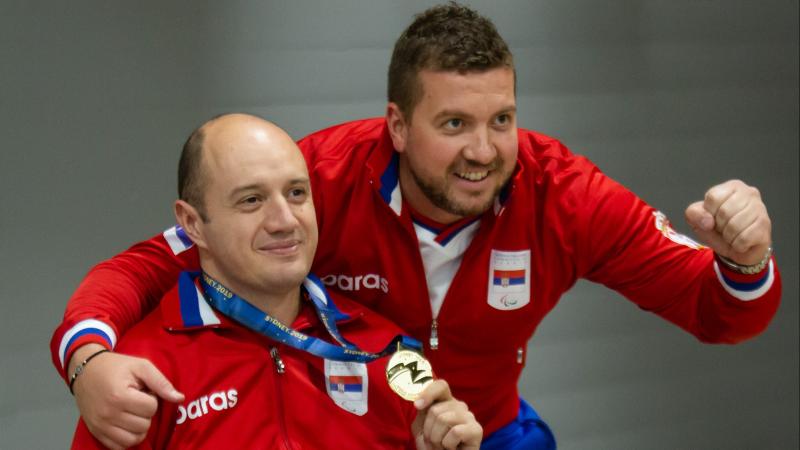 Two Serbian men pose together after winning