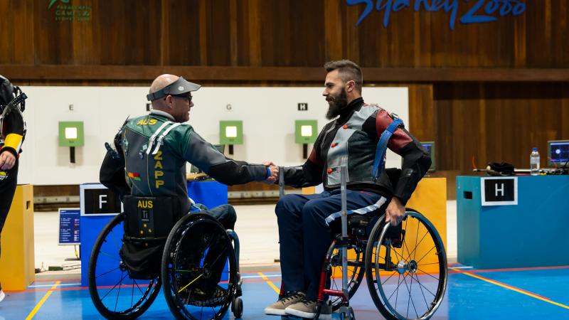 Two men in wheelchairs shake hands