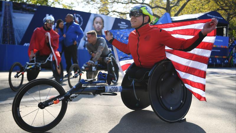 Daniel Romanchuk holds the US flag after winning the 2019 New York Marathon