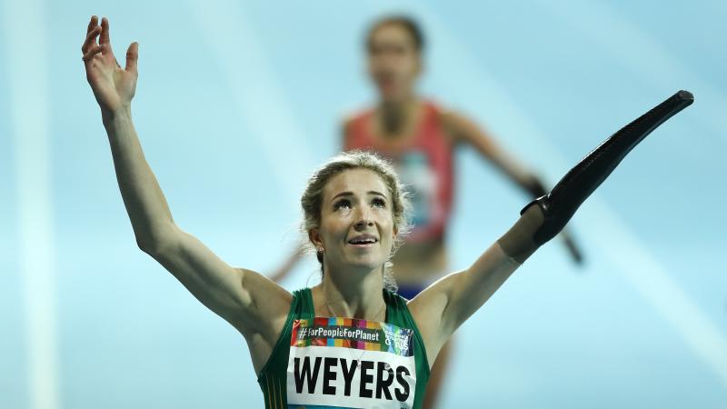 A female runner with a prosthetic arm celebrating