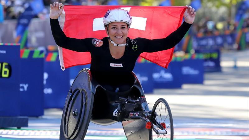 Manuela Schär holds the Swiss flag and smiles to the camera