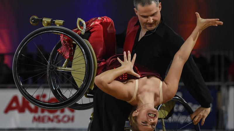 Man in wheelchair dips female wheelchair dance partner