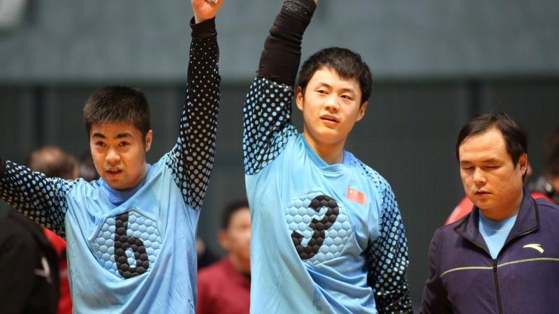 Two Chinese male goalballers raise their arms together in celebration