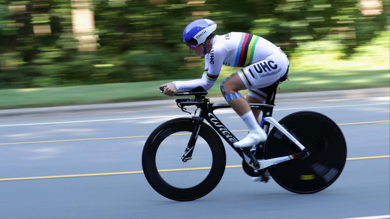 Female cyclist rides on the road with a rainbow jersey