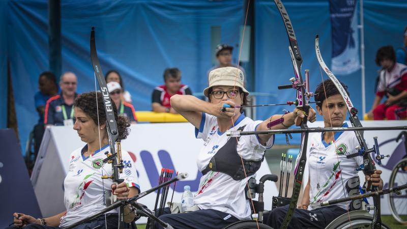 Three Italian female archers lined up while one is about to shoot