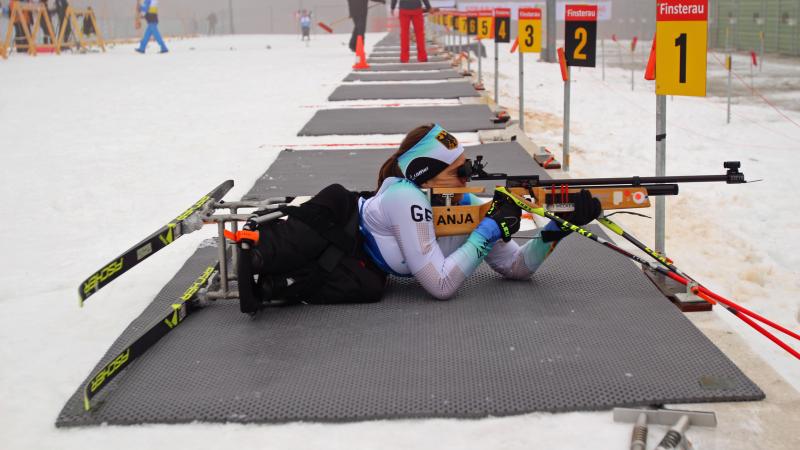 Female sit-skier focuses her rifle in biathlon