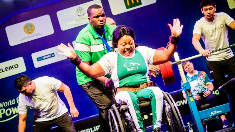 A woman in a wheelchair celebrating with a man standing behind her during a Para powerlifting competition