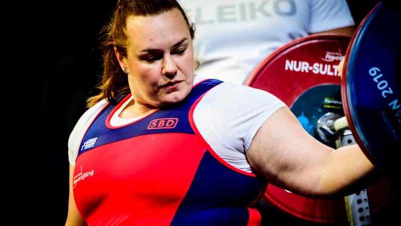 A woman with her hand on a powerlifting bar