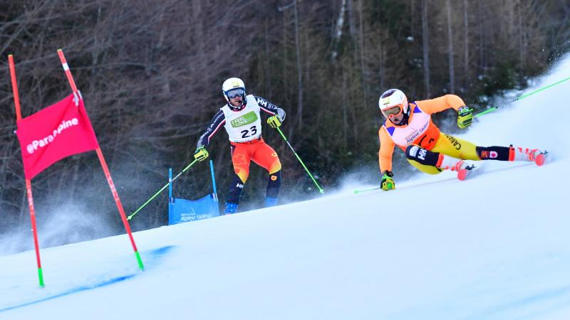 Male alpine skier making a turn with his guide behind him