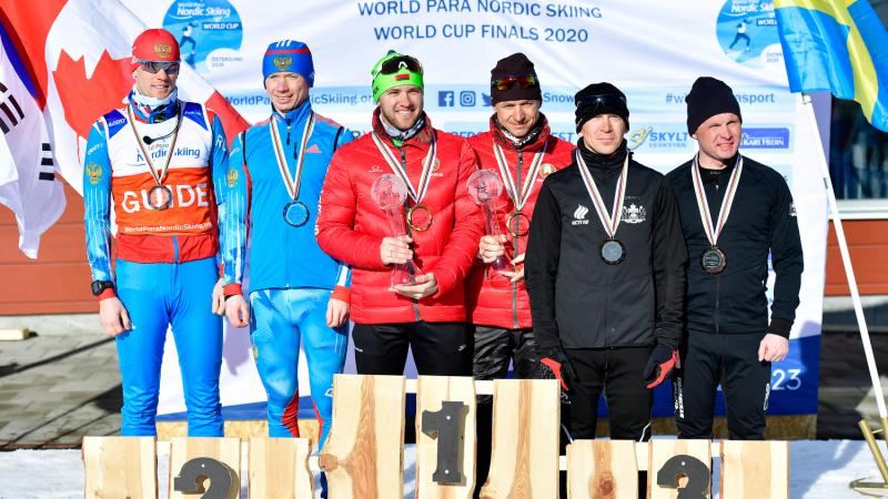 Six men standing on a podium with their medals