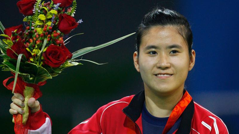 Hoi Ying Karen Kwok smiles while holding flowers with the gold medal on her chest