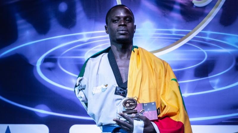 Male African taekwondo player smiles on podium