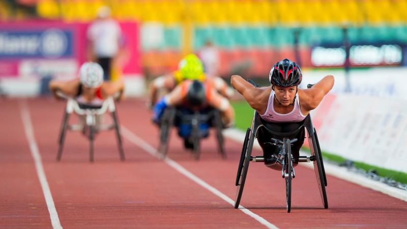 A female wheelchair racer ahead of three other competitors