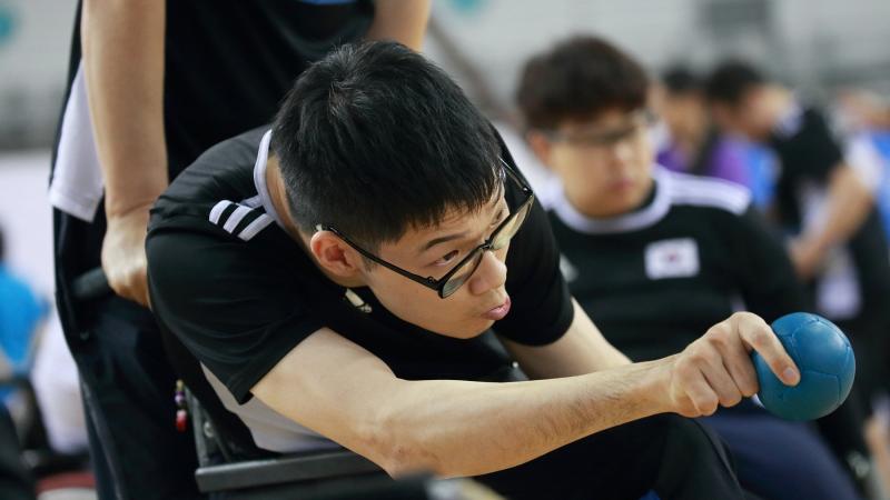 Korean male boccia player about to throw the ball