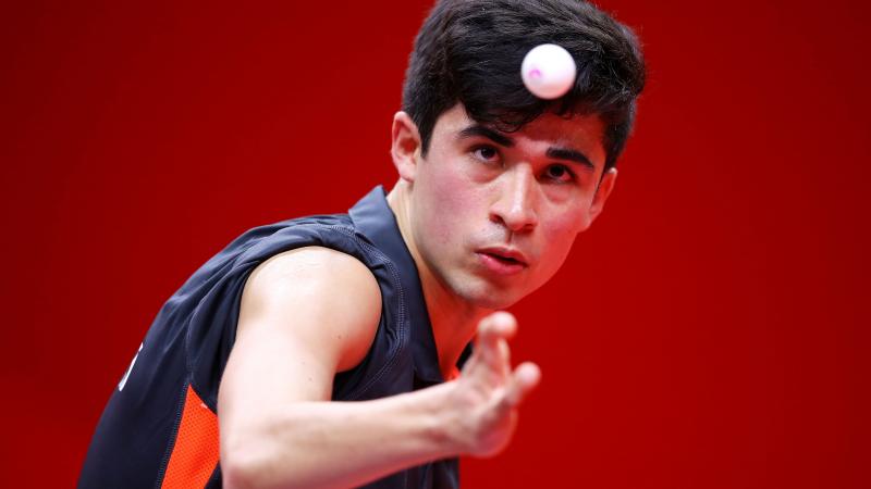 British male Para table tennis player focuses on ball as he is about to serve