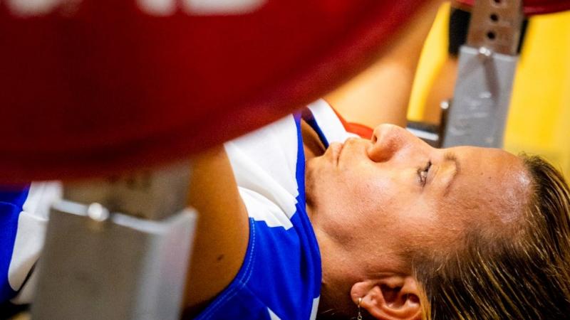 A female powerlifter on a bench preparing to lift the bar