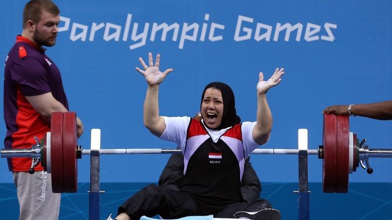 A female powerlifter celebrating being watched by man