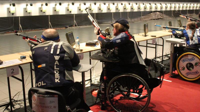 Four people in wheelchairs taking part in a shooting competition