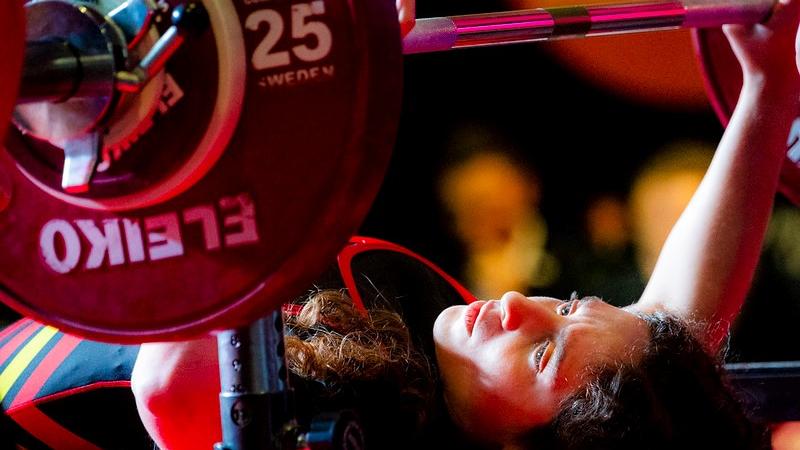 A woman on a bench press preparing to lift the bar