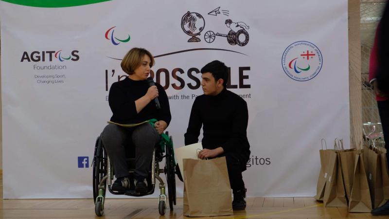 Woman in wheelchair speaks with student winner