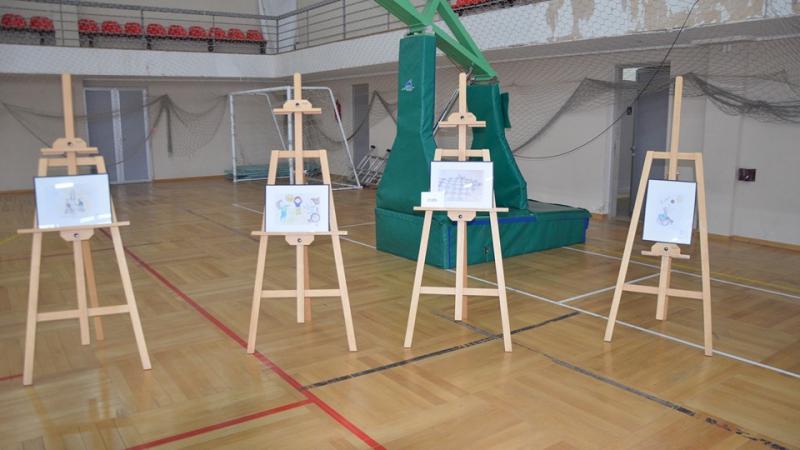 Four artworks being displayed inside a school gymnasium 