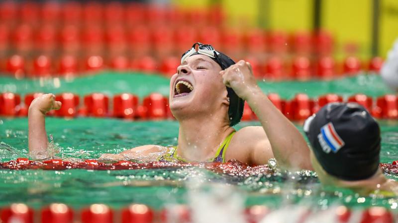 A female swimmer celebrating in the water in front of another athlete