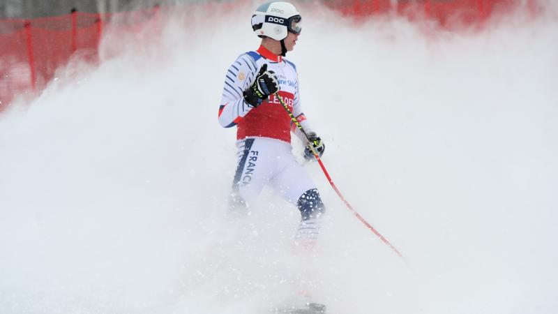 A male skier with a wave of snow behind him