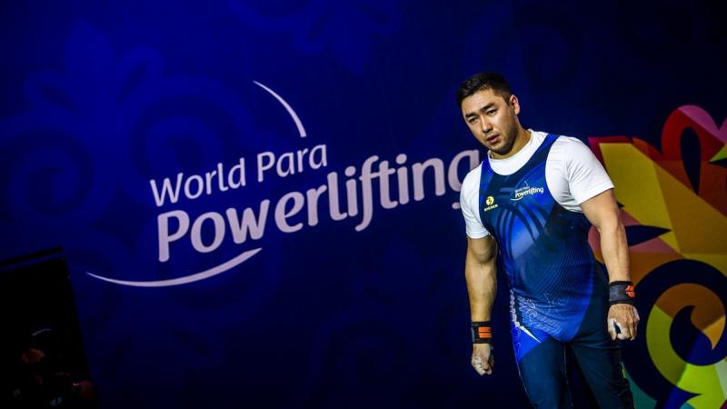 An athlete walking in front of a banner written World Para Powerlifting