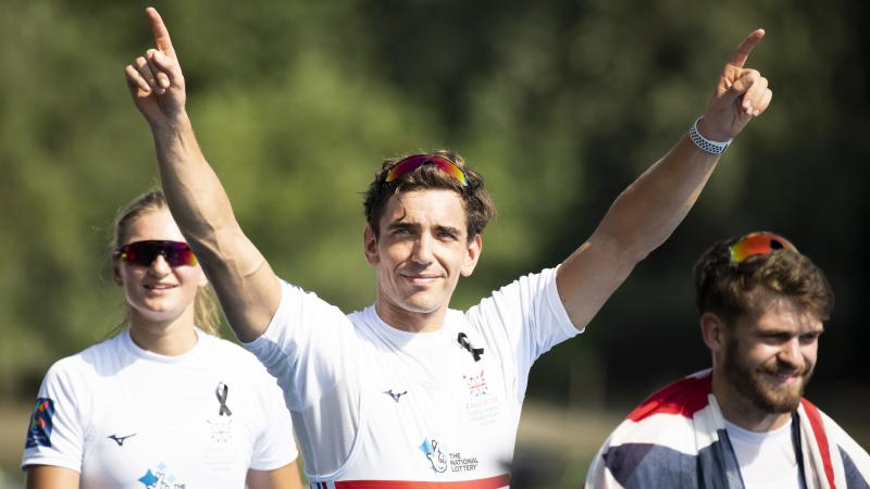 Male British rower smiles with both arms raised