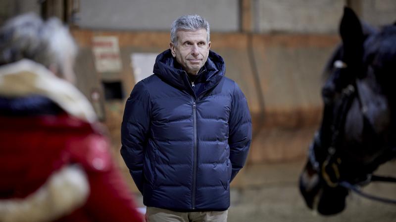 Male coach standing between a horse and person 