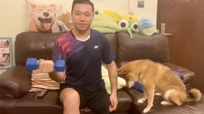Hong Kong man doing bicep curls with dog next to him