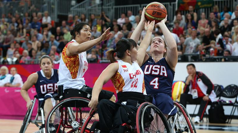 US female wheelchair basketball player shoots the ball while being double teamed