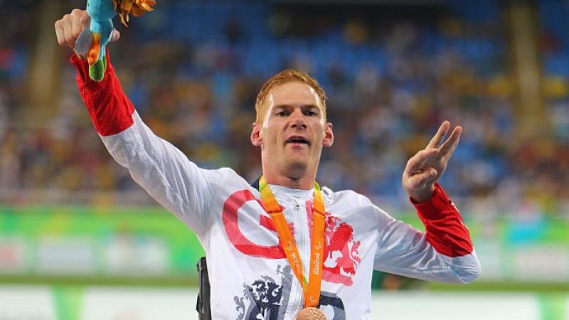 Male British athlete with cerebral palsy celebrates on the podium