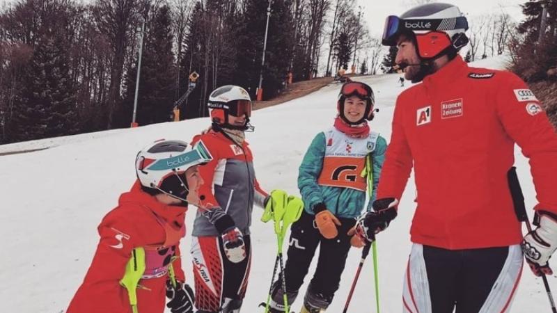 A group of three female and one male skier talking on a ski slope