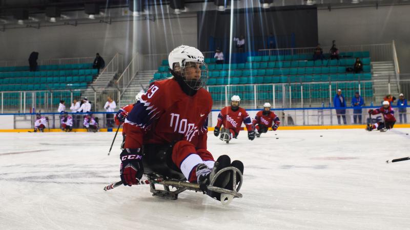 A female Para ice hockey player practising with her teammates on a rink