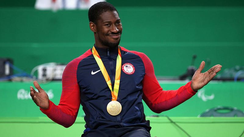 Black male in wheelchair smiling with gold medal around his neck